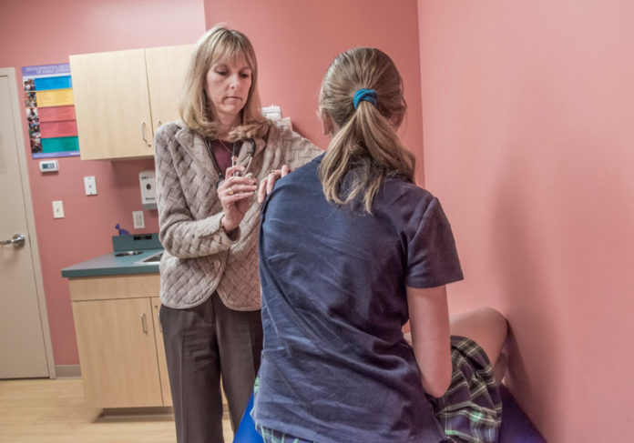 TOP RANKED: Dr. Elizabeth Lange, at Waterman Pediatrics in East Providence, administers a vaccine. Rhode Island ranked first in the U.S. for adolescent vaccination rates, according to the United Health Foundation.