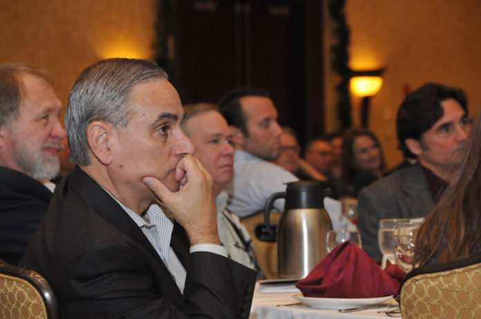 LISTENING IN: Peter LaChapelle, foreground, vice president, operations and finance, NetCenergy LLC, listens to a panel discussion during the PBN Cybersecurity Summit on Dec. 8. / PBN PHOTO/MIKE SKORSKI