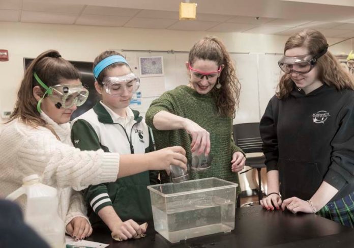 SURFACE TENSION: Suzanne Fogarty, second from right, head of Lincoln School, performs a science experiment looking at water surface tension effects, with sophomore students. From left, Cecelia DiPrete; Kennedy May; Fogarty; and Morgan Hall. / PBN PHOTO/ MICHAEL SALERNO