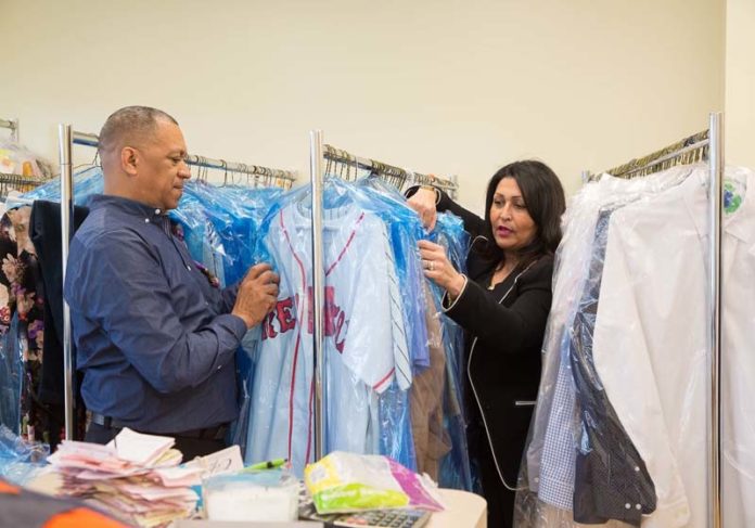 BOUNCING BACK: Ruben D. Ogando, owner of Reymond's Brother Tailor Shop and Laundromat LLC, and his wife, Alba Baez, arrange clothes in the laundromat. Having outgrown his initial space, the laundromat is now located across from his tailoring shop on Cranston Street in Providence. / PBN PHOTO/TRACY JENKINS