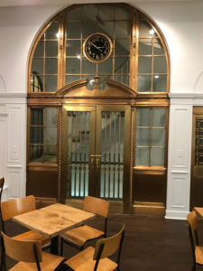 RESTORED: From the newly rehabilitated retail space on the first floor, a set of brass doors opens to the building's secondary stairwell. The stairwell, dating back to the building's inception, was restored and kept in place. / PBN PHOTO/MARK S. MURPHY