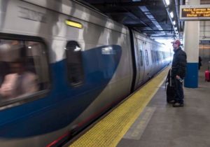MIXED USE: A passenger waits to board a train at Providence Station. The state is seeking to build a transit hub on land  surrounding the station that would also include construction of private development that feeds off the tens of thousands  of commuters and visitors expected to use the transit center. / PBN PHOTO/MICHAEL SALERNO