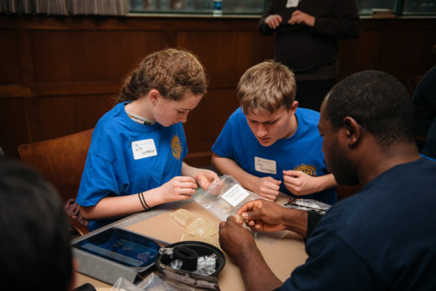ROCKY HILL School freshman Willa Geoghegan of Providence and sophomore John Bergstrom of Portsmouth assemble a 3D-printed hand with New England Institute of Technology Rotaract Club student Arlington Forbes. / COURTESY TREVOR HOLDEN PHOTOGRAPHY