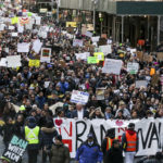 Trump deflects migrant ban chaos by blaming Delta, protesters DEMONSTRATORS HOLD signs and march towards Federal Plaza protesting U.S. President Donald Trump's executive order blocking visitors from seven predominantly Muslim nations in New York on Sunday, Jan. 29. Court decisions temporarily blocked the U.S. administration from enforcing parts of Trump's order after a day in which students, refugees and dual citizens were stuck overseas or detained and some businesses warned employees from those countries not to risk leaving the United States. / BLOOMBERG NEWS PHOTO/JEENAH MOON