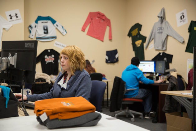 CUSTOM DESIGN: Emily Dickinson, front, is a member of the graphic-design team at Warwick-based SquadLocker, an online software company designed for customized athletic apparel. The company has raised $8.5 million since its founding in 2015. / PBN PHOTO/TRACY JENKINS