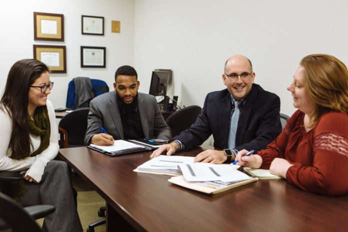 BUDGET SQUEEZE: Michael Souza, second from right, president of the Hospital Association of Rhode Island, works with staff members, from left, Liz Almanzor, director of financing; Melvin Smith, government-relations manager; and Amanda Barney, vice president. / PBN PHOTO/RUPERT WHITELEY