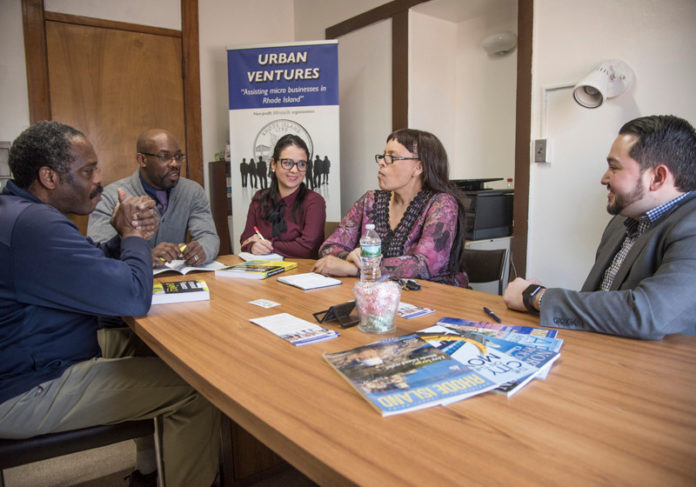 PBN PHOTO/ MICHAEL SALERNO / PERSEVERANCE: Urban Ventures Executive Director JR Neville Songwe, second from left, meets with staff and microbusiness owners. The public incubator, which continues to operate, is at risk of closing due to loss of funds.
