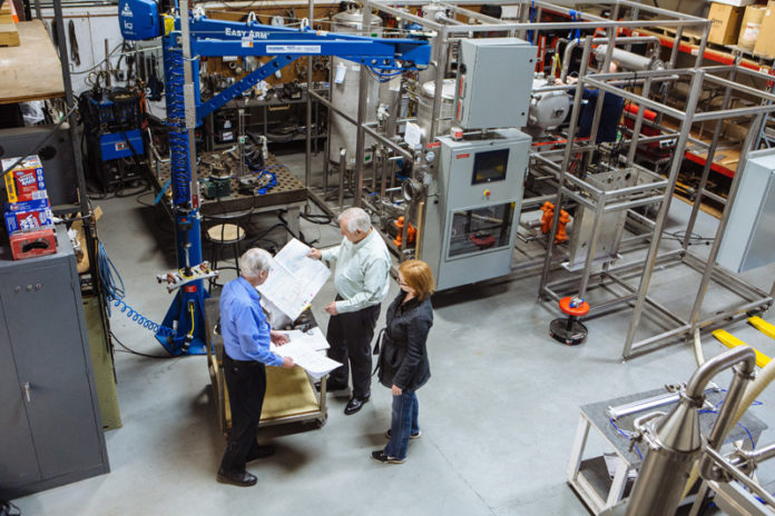 A LEAP FORWARD: From left, Don Gray and Joseph Schuttert, company principals, and Jessica Weimar, operations manager, look over schematics at Vaccum Processing Systems' East Greenwich facility. / PBN PHOTO/RUPERT WHITELEY