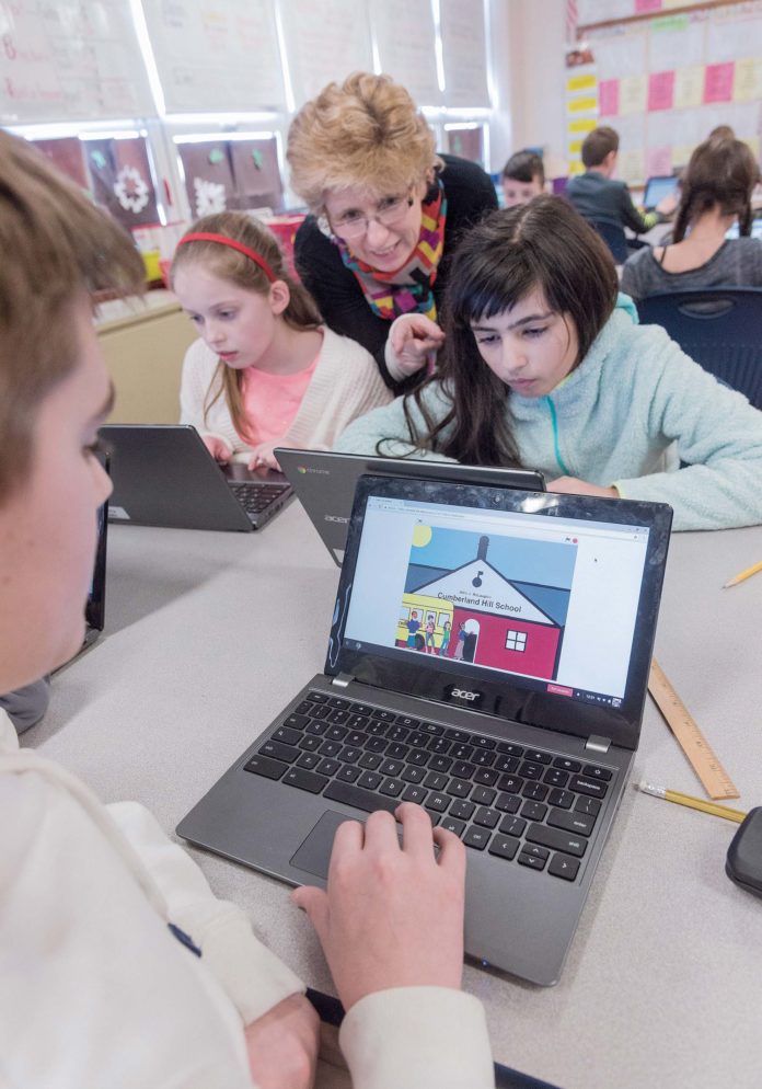 NEW SKILLS: Bernadette Durkin is using the skills she learned during the October 2016 Rhode Island College and General Assembly computer science boot camp to help her fifth-grade class at Cumberland Hill School in Cumberland learn to code. From left, Luke Plumer, 11, foreground; Leah Mandeville, 11; Durkin; and Adriana Panagoulopoulos, 10. / PBN PHOTO/MICHAEL SALERNO
