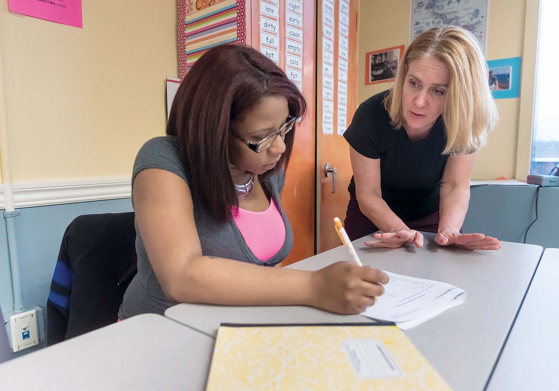 HELPING HAND: Amanda Hanley, right, transition councilor for Rhode Island Regional Adult Learning, assists Esther Alvarez, of Woonsocket, as part of an adult-education class for workers learning English skills. / PBN PHOTO/MICHAEL SALERNO