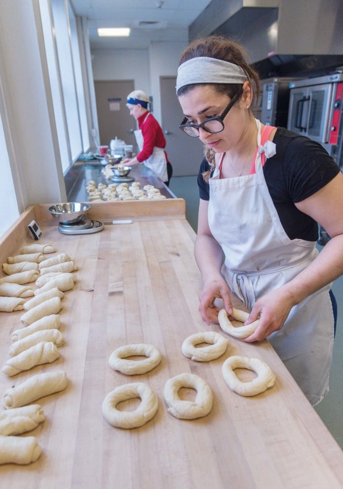 Milena Pagan, owner of Rebelle Artisan Bagels, at Hope & Main in Warren working on producing product for customers. In the background is Rebecca Atwood, baker. PBN PHOTO/MICHAEL SALERNO