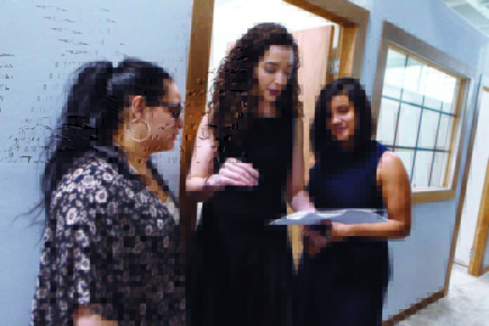 PURPOSEFUL ACHIEVEMENT: Libby Kimzey, center, the Capital Good Fund’s chief operating officer, is instrumental in the nonprofit lender’s success, including expanding its offices. Here, she confers with loan officers Heiry Bulux, left, and Vanessa Ramirez. / PBN PHOTO/RUPERT WHITELEY