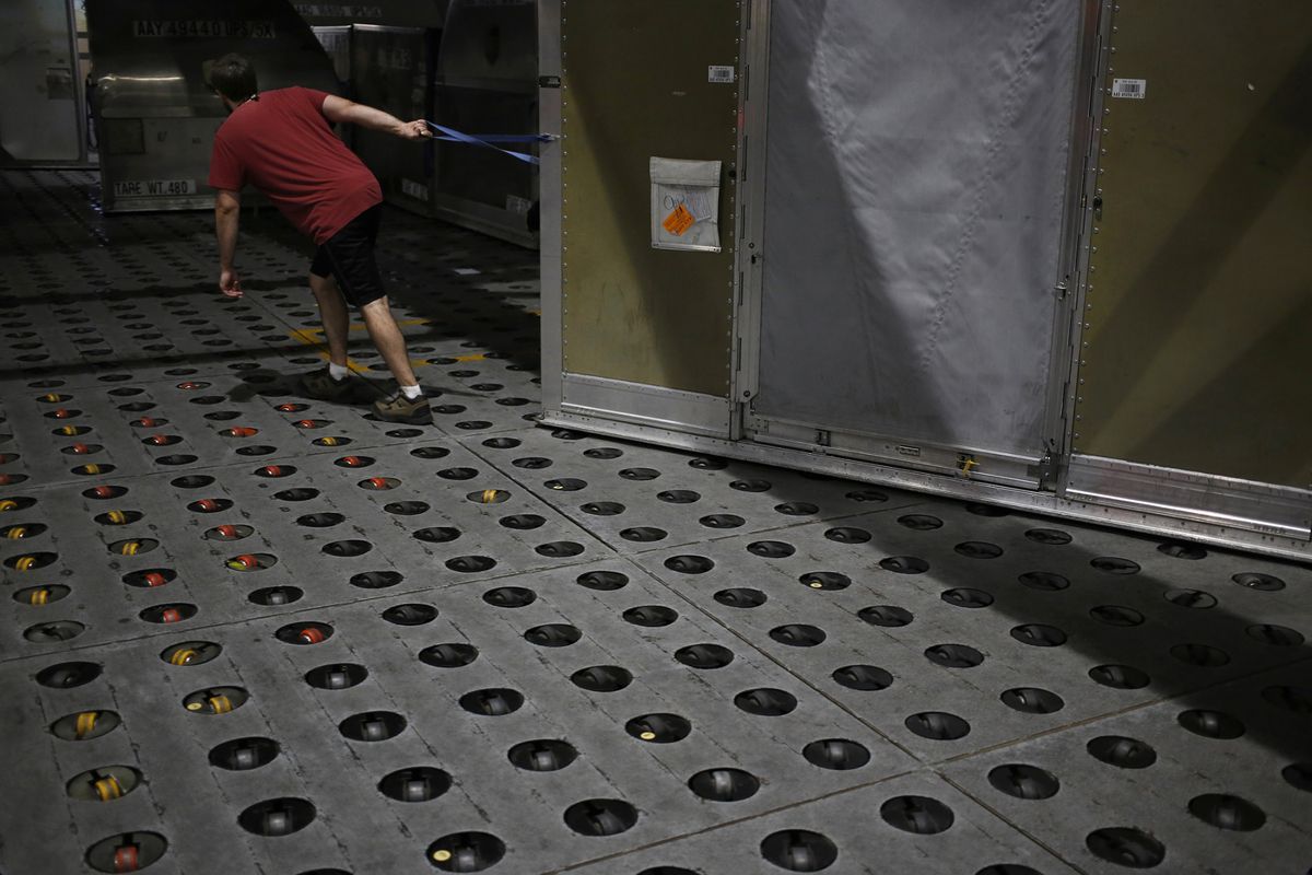 A WORKER drags a package container inside to be unloaded during the night package sort at a facility in Louisville, Kentucky. /BLOOMBERG NEWS PHOTO/ LUKE SHARRETT