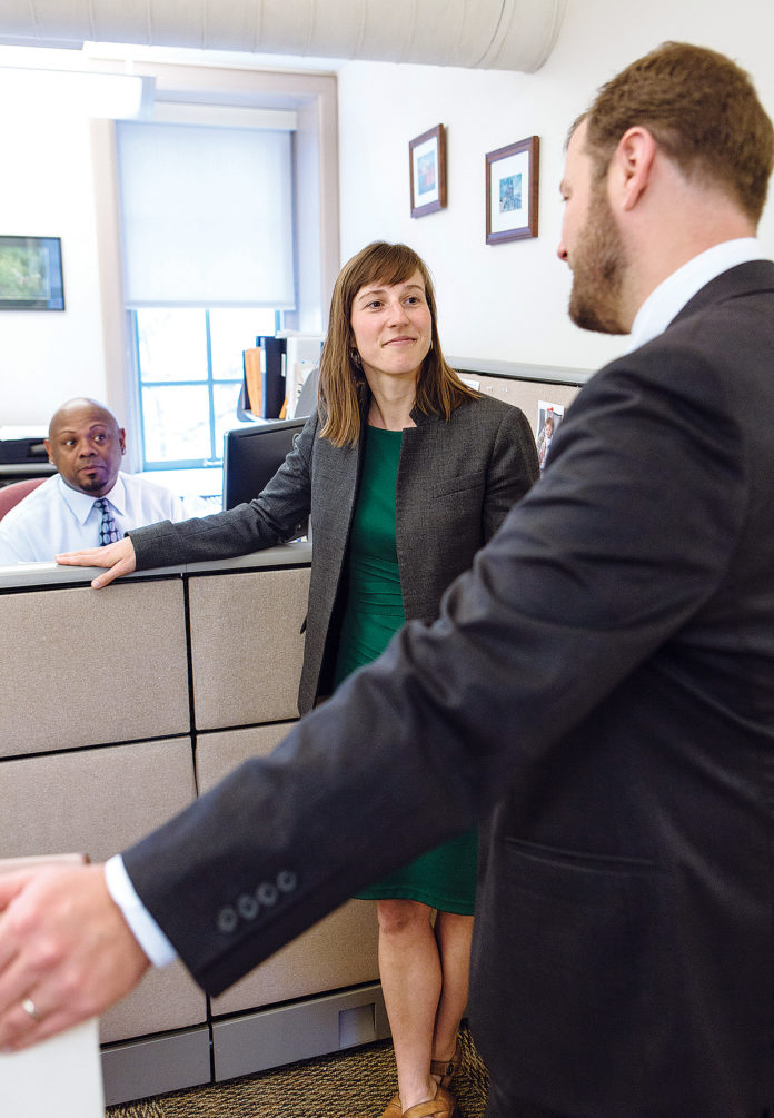 COLLABORATIVE EFFORT: Heather Hudson, executive director of the Governor’s Workforce Board, talks with Spencer Dickinson, foreground, Prepare RI project director, and Daniel Brown, GWB chief implementation aid, at the R.I. Department of Labor and Training building in Cranston. / PBN PHOTO/RUPERT WHITELEY