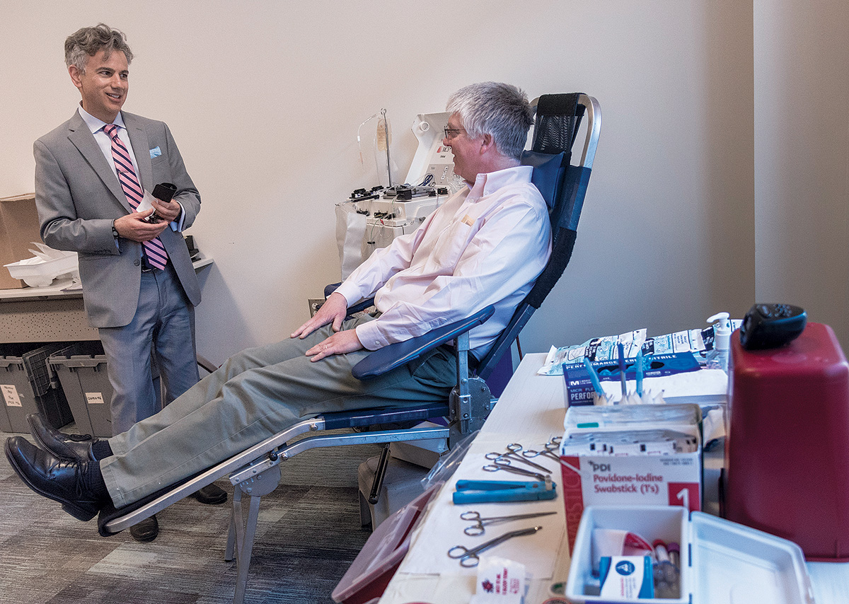 A REGULAR APPOINTMENT: Anthony Bogar, right, of East Providence, gives blood every eight weeks. Following a recent donation at Blue Cross & Blue Shield of Rhode Island offices in Providence, he speaks with Scott J. Asadorian, the Rhode Island Blood Center’s vice president and chief operating officer. / PBN PHOTO/­MICHAEL SALERNO