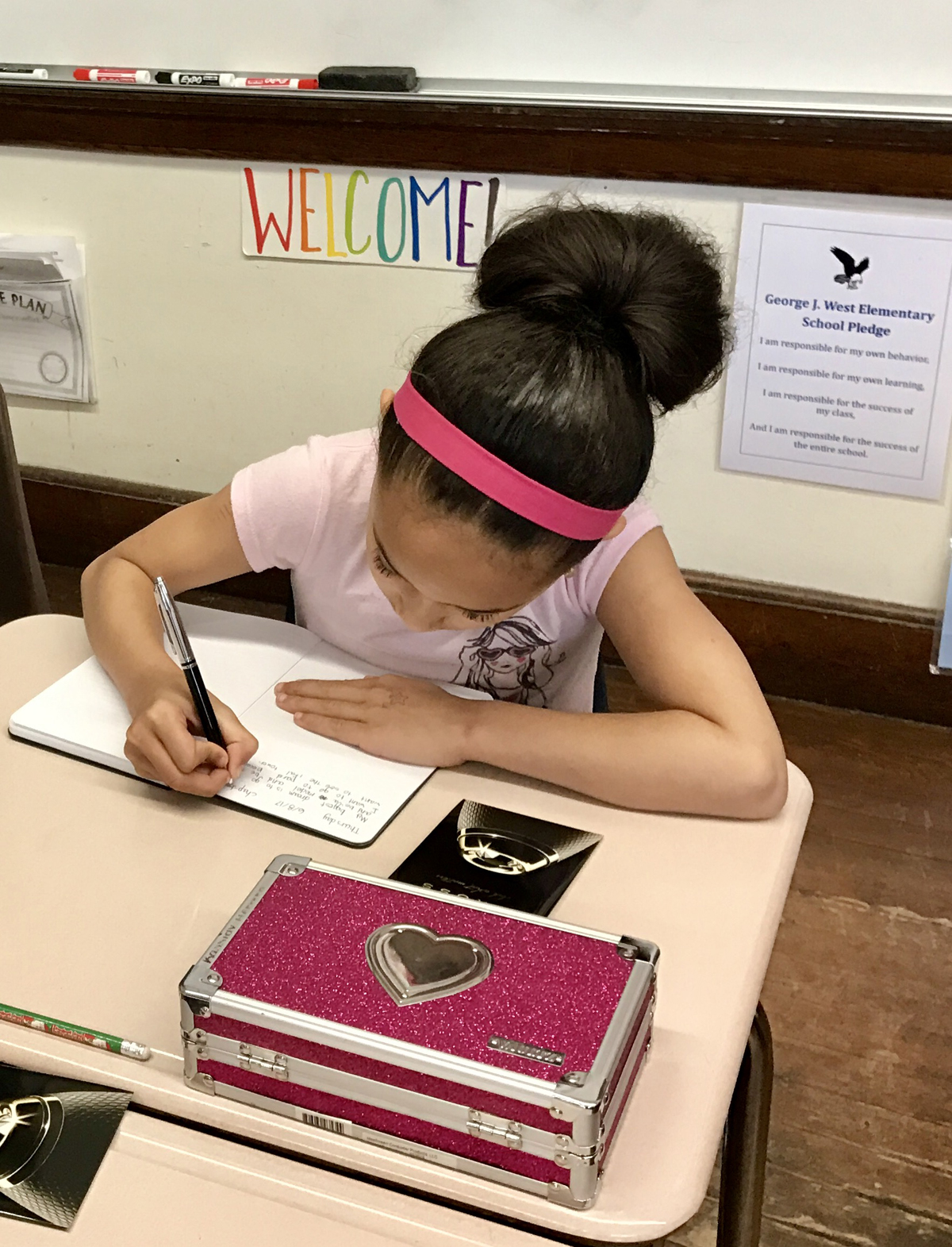 TO AVOID LOSS of reading skills over the summer months while out of school, writing tools manufacturer A.T. Cross donated 900 of their ballpoint pens and lined journals with pen holders to students at George J. West Elementary School in Providence during the school's Reading Week. Pictured, a student from Tracie Gagnon's second-grade class writes in her journal. /COURTESY A.T. CROSS