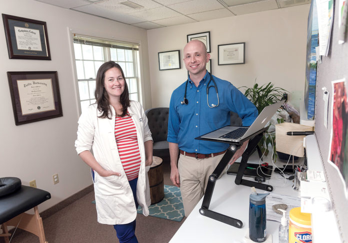 MEETING A NEED: Dr. Mark Turshen and Dr. Lauren Hedde, co-owners of Direct Doctors Inc., a health care provider, at their North Kingstown office. The pair started the “direct primary care” practice after identifying a shortage of primary care doctors during their residency together at Brown University. / PBN PHOTO/MICHAEL SALERNO MEETING A NEED: Dr. Mark Turshen and Dr. Lauren Hedde, co-owners of Direct Doctors Inc., a health care provider, at their North Kingstown office. The pair started the “direct primary care” practice after identifying a shortage of primary care doctors during their residency together at Brown University. / PBN PHOTO/MICHAEL SALERNO