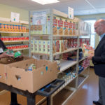 INCREASED RELIANCE: Rhode Island Community Food Bank CEO Andrew Schiff helps volunteer Yve Capella stock the shelves at The Olneyville Food Center at 261 Manton Ave., in Providence. Schiff says there is an increased reliance on emergency food pantries fed by the food bank in the summer months when free and reduced-priced school-meal services are paused, putting greater strain on low-income families to afford food. / PBN PHOTO/MICHAEL SALERNO