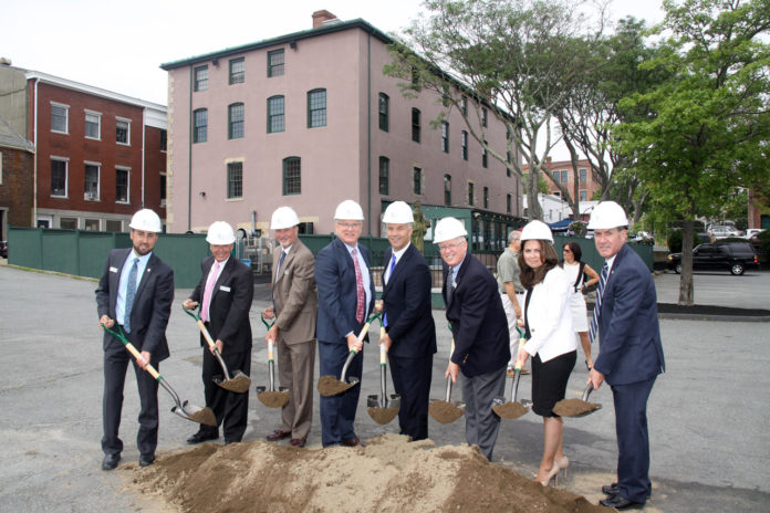 BRISTOL COUNTY SAVINGS BANK officials and New Bedford Mayor Jon Mitchell participate in the ceremonial groundbreaking of the bank's third New Bedford branch, offices of which will be located in the Candleworks building (background). Pictured, from left, are: Michael Patacao, vice president/commercial lending; Len Sullivan, first executive vice president and senior loan officer; Pete Selley, senior vice president/commercial lending; Patrick J. Murray Jr., president and CEO; Mitchell; Dennis Kelly, chairman of the board; Nancy Cabral, branch manager; and David Medeiros, vice president, regional banking officer. /COURTESY BRISTOL COUNTY SAVINGS BANK