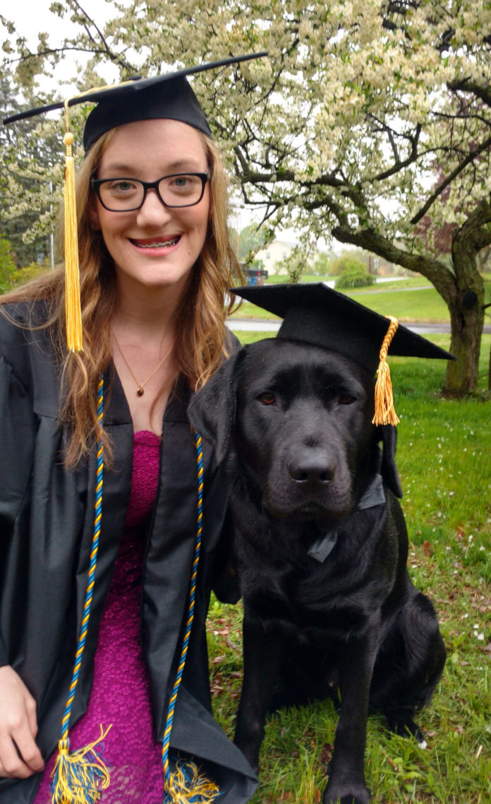 UNIVERSITY OF RHODE ISLAND senior Caitlyn Landry and Navy, a black lab she has trained for a year to become a guide dog, prepare for graduation. /COURTESY UNIVERSITY OF RHODE ISLAND/NORA LEWIS