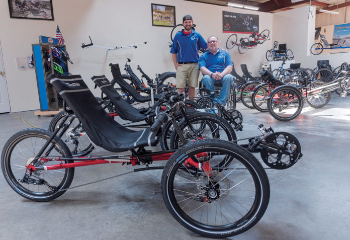 ADAPTIVE CYCLES: Scott Pellett, founder and CEO of Bike-On, was paralyzed from the waist down at age 15. Bike-On is an online retailer of recumbent trikes and adaptive cycles. With Pellett is employee Chris Coyne. / PBN PHOTO/MICHAEL SALERNO