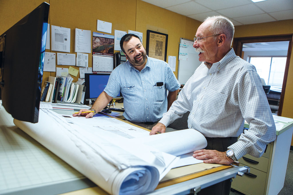 IN DEMAND: Edward W. Burman Jr., right, president of general contractor E.W. Burman Inc. in Warwick, talks with estimator Bob Dandeneau. The firm was recently contracted to construct University Orthopedics in East Providence and the Welcome Center at the South Kingstown campus of the University of Rhode Island. / PBN PHOTO/RUPERT WHITELEY