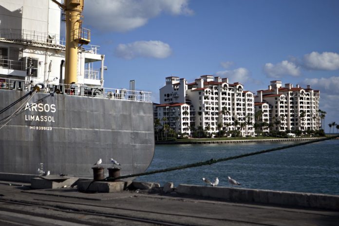 CONDOMINIUMS ON FISHER Island are seen past the Arsos container ship in the port of Miami. / BLOOMBERG FILE PHOTO/ANDREW HARRER