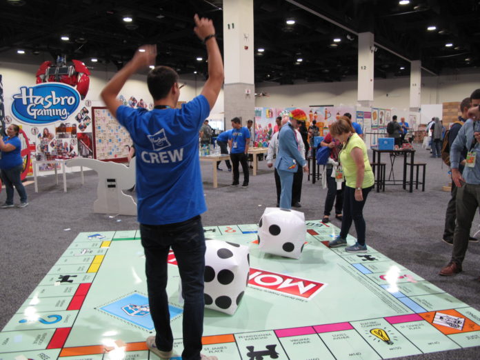 HasCon attendees and staff take turns throwing dice on a Monopoly board, one of many larger-than-life games at the event. PBN PHOTO/NICOLE DOTZENROD