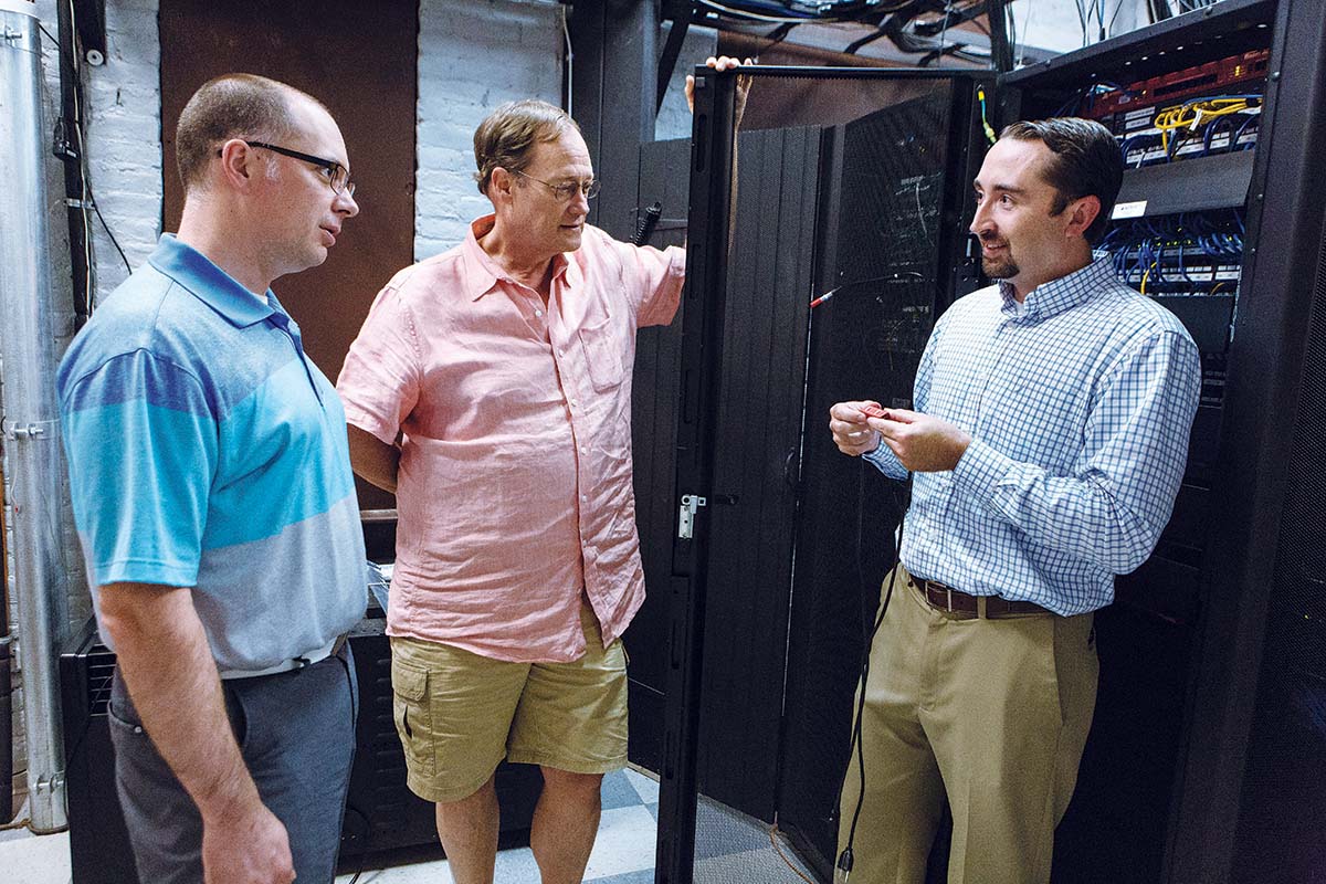 SMALL PRODUCT, big LEAP: Rich Grundy, right, president of AVTECH Software, talks about the company’s new Active Power Sensor with Marketing Manager Russel Benoit, left, and company founder and CEO Michael Sigourney, middle. / PBN PHOTO/RUPERT WHITELEY