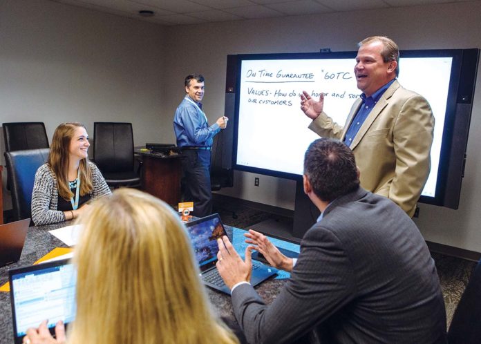 HUMAN INVESTMENT: Embrace Home Loans leaders help people finance “homes where memories are made.” A key to that effort is in-house training. Engaged in conversatiom are Nicholas DeLuca, middle, Al Dussinger, right, and attendee Lillia Wild. / PBN PHOTO/RUPERT WHITELEY