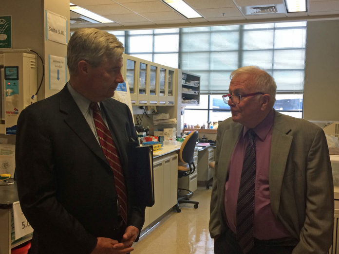 U.S. SEN. SHELDON Whitehouse, left, and Lifespan primary investigator Dr. Peter J. Quesenberry discuss his team’s research at Lifespan’s research lab at 1 Hoppin St. in Providence. / PBN PHOTO/ROB BORKOWSKI