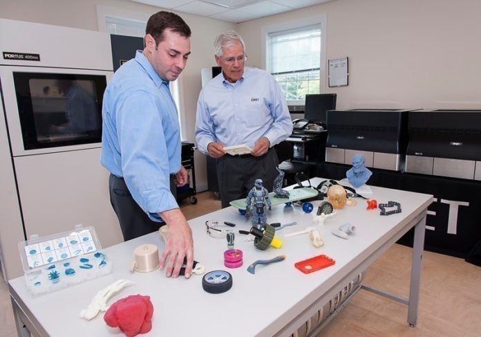 R&D TECHNOLOGIES will hold the grand opening of its additive manufacturing center in North Kingstown on Oct. 20. Above, from left, Justin and Andrew Coutu, president and CEO of the company, respectively, show off some of the objects produced in the company's 3-D printing-service bureau. / PBN FILE PHOTO/MICHAEL SALERNO