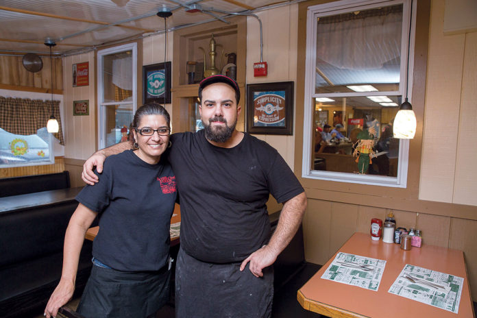DEDICATED: Owner Christos Kirios and waitress Brenda Richer at the Middle of Nowhere Diner in Exeter. Kirios says he works in the kitchen six days a week because it sends a message to the employees that the owner is involved. / PBN PHOTO/
TRACY JENKINS DEDICATED: Owner Christos Kirios and waitress Brenda Richer at the Middle of Nowhere Diner in Exeter. Kirios says he works in the kitchen six days a week because it sends a message to the employees that the owner is involved. / PBN PHOTO/
TRACY JENKINS
