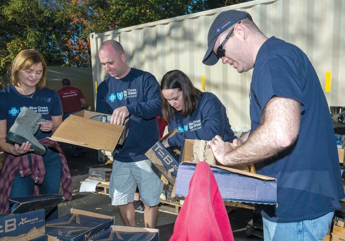 VALUED AND IMPACTFUL: Blue Cross & Blue Shield of Rhode Island volunteers on-site of the Operation Stand Down project in Johnston. They are sorting through the boots that were part of an in-store promotion by Job Lot, buy boots for a vet and get a gift card. From left, Sindy Guderle, nurse case manager; Gabe Goodine, director business operations; Andrea Camara, medical policy analyst; Sam Burling, senior financial analyst. / PBN PHOTO/MICHAEL SALERNO