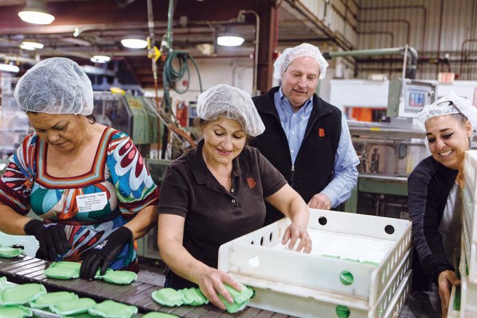 CLEAN TEAM: Stuart R. Benton, president and CEO of Bradford Soap Works, tours the factory and talks with workers in West Warwick. From left are Blanca Johnson Lopez, packer; Maria Medeiros, group leader; Benton; and Carleen Conklin, machine operator. / PBN PHOTO/RUPERT WHITELY CLEAN TEAM: Stuart R. Benton, president and CEO of Bradford Soap Works, tours the factory and talks with workers in West Warwick. From left are Blanca Johnson Lopez, packer; Maria Medeiros, group leader; Benton; and Carleen Conklin, machine operator. / PBN PHOTO/RUPERT WHITELY