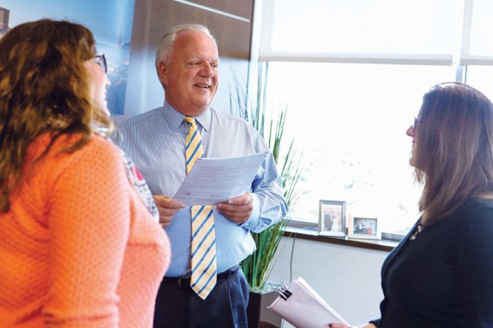 PROSPEROUS HISTORY: William A. “Bill” White, Coastway president and CEO, speaks with Katie MacDonald, left, marketing manager, and Jeanette Fitz, chief financial officer, at the bank’s Providence office.  / PBN PHOTO/RUPERT WHITELY