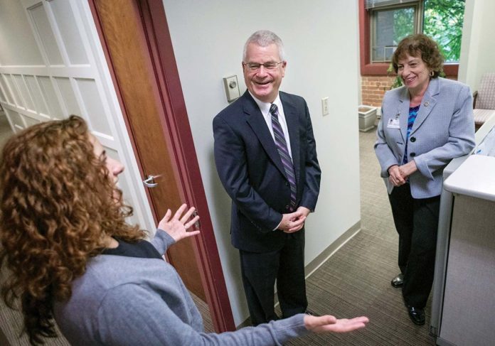 DYNAMIC DEDICATION: Dennis D. Keefe, retiring president and CEO of Care New England, speaks with Malinda Caetano, executive assistant, left, and Frances Giatas, executive assistant to Keefe, at their Providence office. / PBN PHOTO/MICHAEL SALERNO DYNAMIC DEDICATION: Dennis D. Keefe, retiring president and CEO of Care New England, speaks with Malinda Caetano, executive assistant, left, and Frances Giatas, executive assistant to Keefe, at their Providence office. / PBN PHOTO/MICHAEL SALERNO