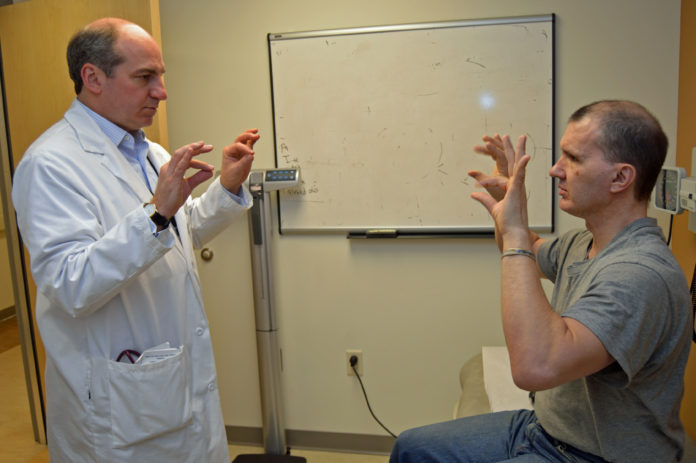 DR. W. CURT LAFRANCE, co-principal investigator for a new study that hopes to shed light on the mechanism behind seizures associated with post-traumatic epilepsy and psychogenic nonepileptic seizures, conducts a finger-tapping exercise with Army and Navy Veteran Ernest J. Avery of West Warwick as part of an exam at the Providence VA Medical Center. Seizures are a common result of traumatic brain injury, especially in Veterans. / COURTESY OCEAN STATE RESEARCH INSTITUTE