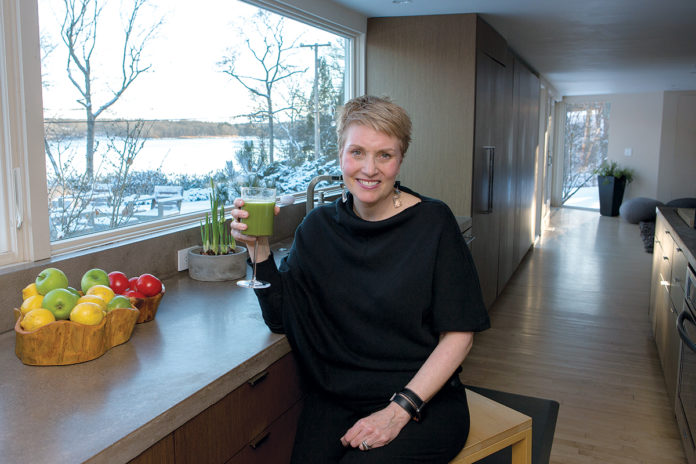 COLD CURE: Katie McDonald, corporate health coach and owner of bnourished, sits at her kitchen counter enjoying a green juice, a remedy/prevention for winter colds. / PBN PHOTO/KATE WHITNEY LUCEY COLD CURE: Katie McDonald, corporate health coach and owner of bnourished, sits at her kitchen counter enjoying a green juice, a remedy/prevention for winter colds. / PBN PHOTO/KATE WHITNEY LUCEY