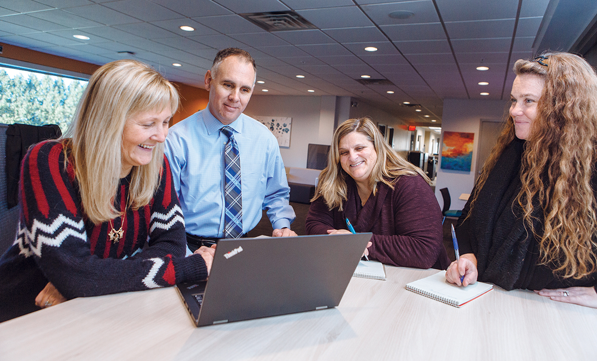 COMMUNITY CONNECTION: Kurt Noyce, president of Embrace Home Loans Inc. in Middletown, said the company’s relationship with local colleges and job-development organizations has provided Embrace with “eager, energetic and ethical employees.” Pictured, from left: Claudia Mobilia, senior vice president of loan operations; Noyce; Shawn Cary, bank finance manager; and Shannon Timek, closing team leader. / PBN FILE PHOTO/RUPERT WHITELEY