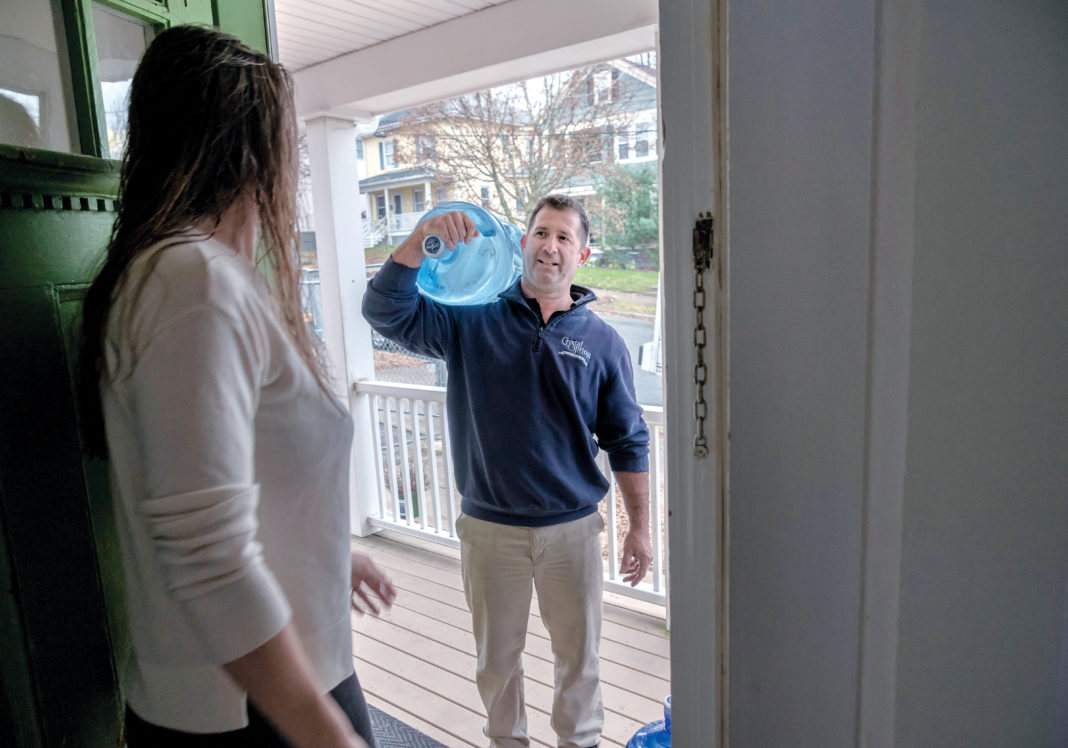 CONTAMINANT FREE: Paul Cicillini, carrier for Crystal Springs Water Co., delivers water to the apartment of Natalie Drozhzhin in Providence. Customers are willing to pay monthly for delivery of drinking water they know is free of contaminants. / PBN PHOTO/MICHAEL SALERNO CONTAMINANT FREE: Paul Cicillini, carrier for Crystal Springs Water Co., delivers water to the apartment of Natalie Drozhzhin in Providence. Customers are willing to pay monthly for delivery of drinking water they know is free of contaminants. / PBN PHOTO/MICHAEL SALERNO