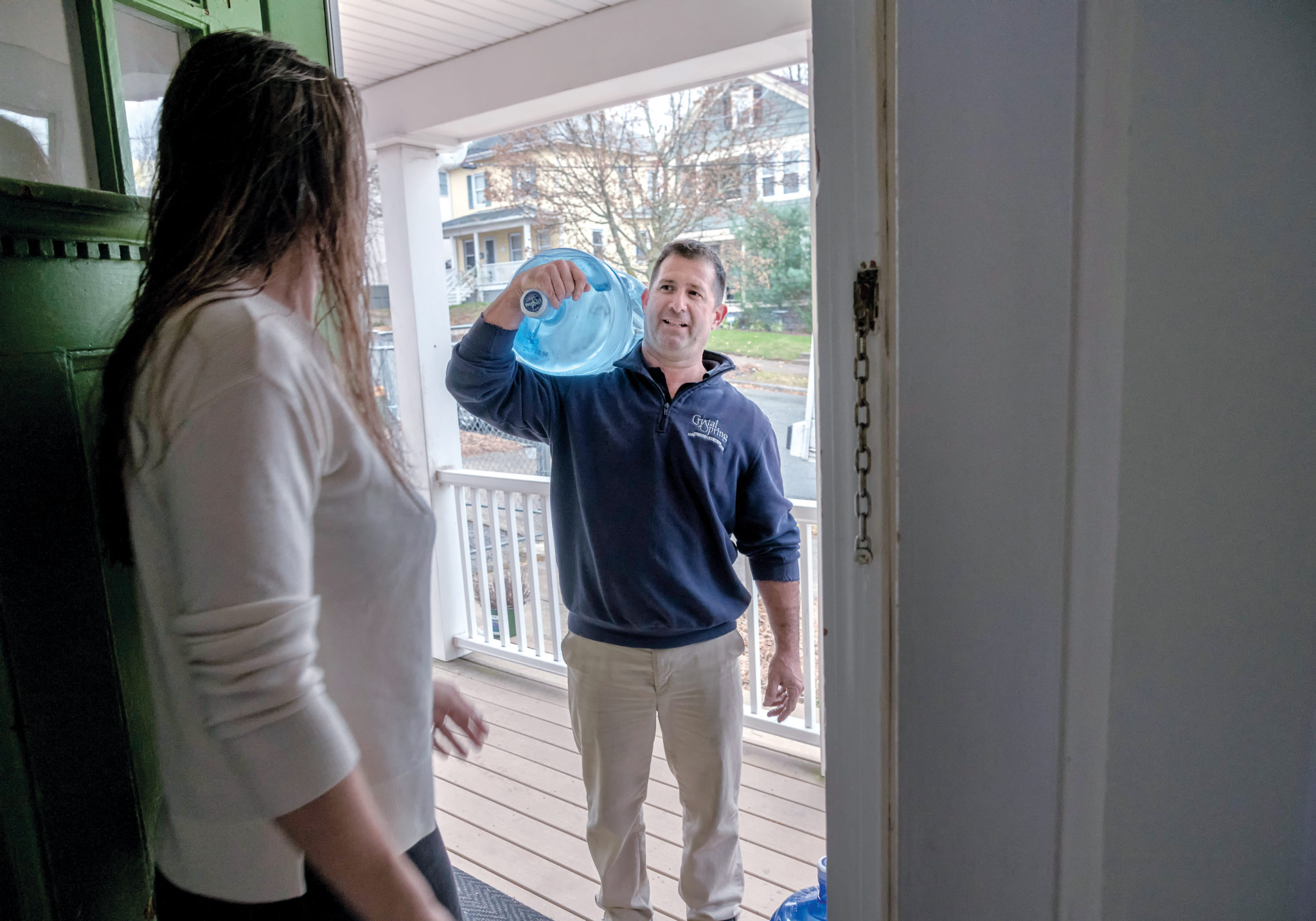 CONTAMINANT FREE: Paul Cicillini, carrier for Crystal Springs Water Co., delivers water to the apartment of Natalie Drozhzhin in Providence. Customers are willing to pay monthly for delivery of drinking water they know is free of contaminants. / PBN PHOTO/MICHAEL SALERNO