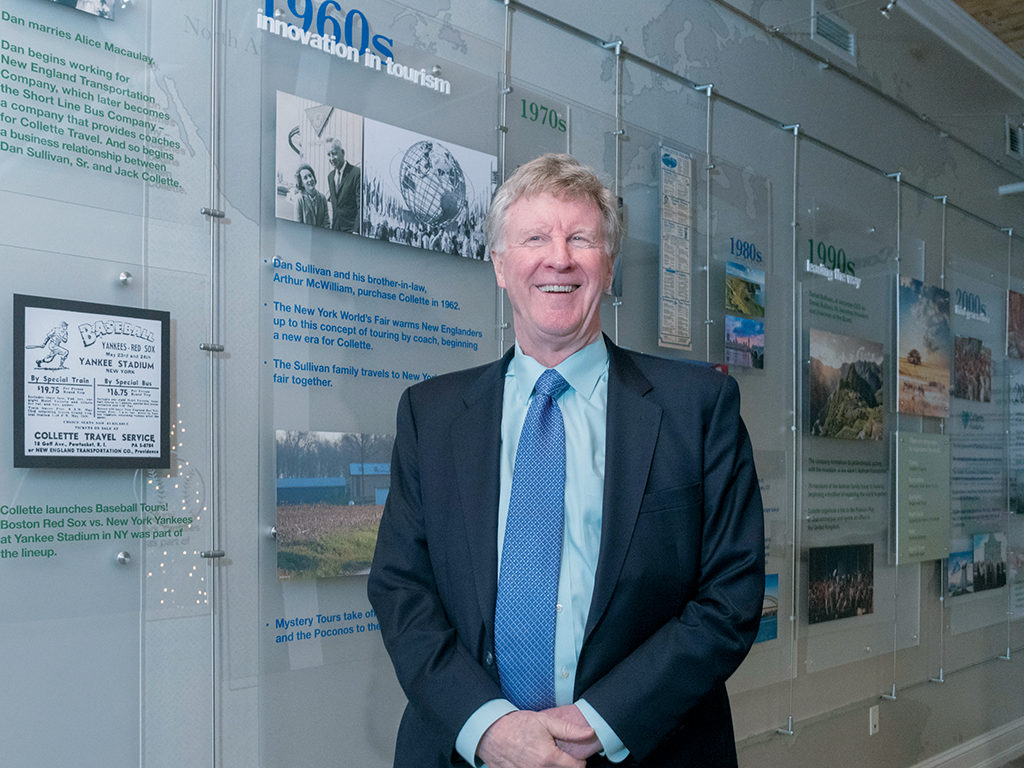 FAMILY OWNED: Collette CEO and President Dan Sullivan Jr. stands in front of the company’s timeline at its Pawtucket headquarters. Sullivan succeeded his father, Dan Sullivan, as CEO in 1990. / PBN PHOTO/MICHAEL SALERNO