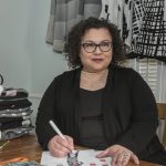 NEW ­DESIGNS: Elana Carello, owner of Elana Carello Sweaters, sketches new designs. She has found success in pop-up shops and artisan shows and has seen her sales grow. / PBN PHOTO/­MICHAEL SALERNO
