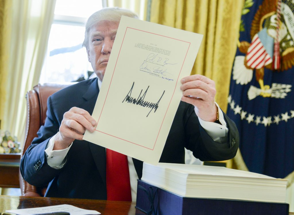 PRESIDENT DONALD TRUMP holds up the tax overhaul legislation after signing it on Dec. 22, 2017. / BLOOMBERG NEWS FILE PHOTO