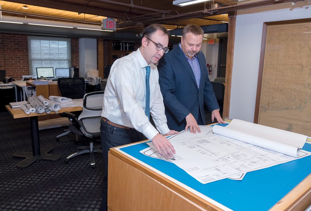 LOOKING AHEAD: David L. DeQuattro, right, managing principal of Providence-based RGB Architects, looks at building plans with Martin Holland, job captain. DeQuattro anticipates an increase in construction business in the Ocean State in 2018. / PBN PHOTO/MICHAEL SALERNO