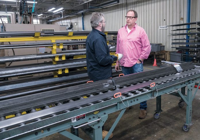 CONCERNED: Dave Waldeck, left, fabrication supervisor at VIBCO Vibrators in Richmond, speaks with CEO Karl Wadensten. VIBCO uses aluminum and steel in about 75 percent of its products and is scrambling to find enough supply and to find an agreeable price for future shipments. / PBN PHOTO/­MICHAEL SALERNO