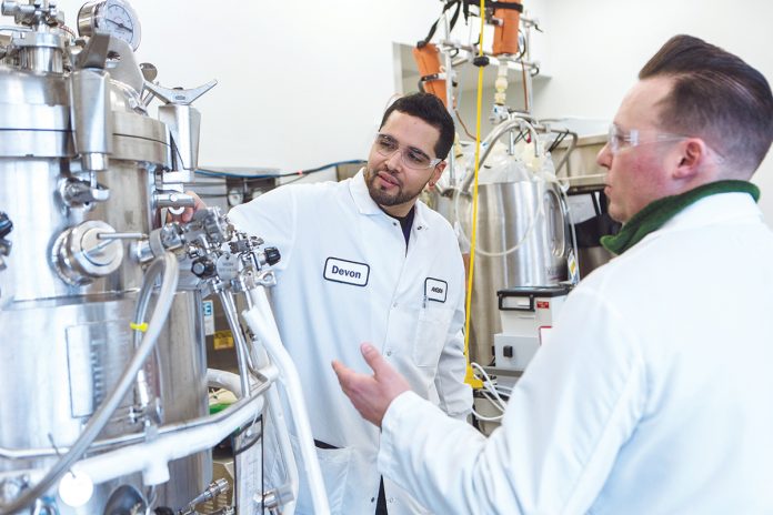 SAFETY BRIEFING: Devon Zayas, left, and Scott Lyons, senior associates in the process-development division at Amgen’s laboratory in West Greenwich, conduct a pre-job safety briefing for hand-valve manipulations on the 100-liter stainless-steel bioreactor. / PBN PHOTO/RUPERT WHITELEY