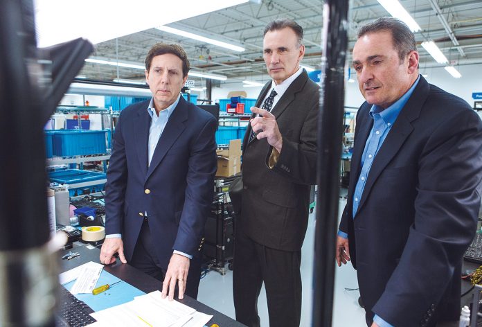 SUPPLY AND COMMAND: From left, AstroNova CEO Gregory Woods, Purchasing Manager James McGovern and Vice President of Instrument Manufacturing Stephen Petrarca review the company’s new vendor-owned/managed inventory system. / PBN PHOTO/RUPERT WHITELEY
