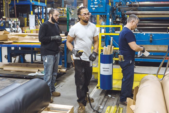 ON A ROLL: From left, Cooley Group employees Bo LeBlue, Cas Pereira and Joe Mello convert a finished goods roll of CoolGuard liner material, often used to line reservoirs, to the proper size.   / PBN PHOTO/RUPERT WHITELEY